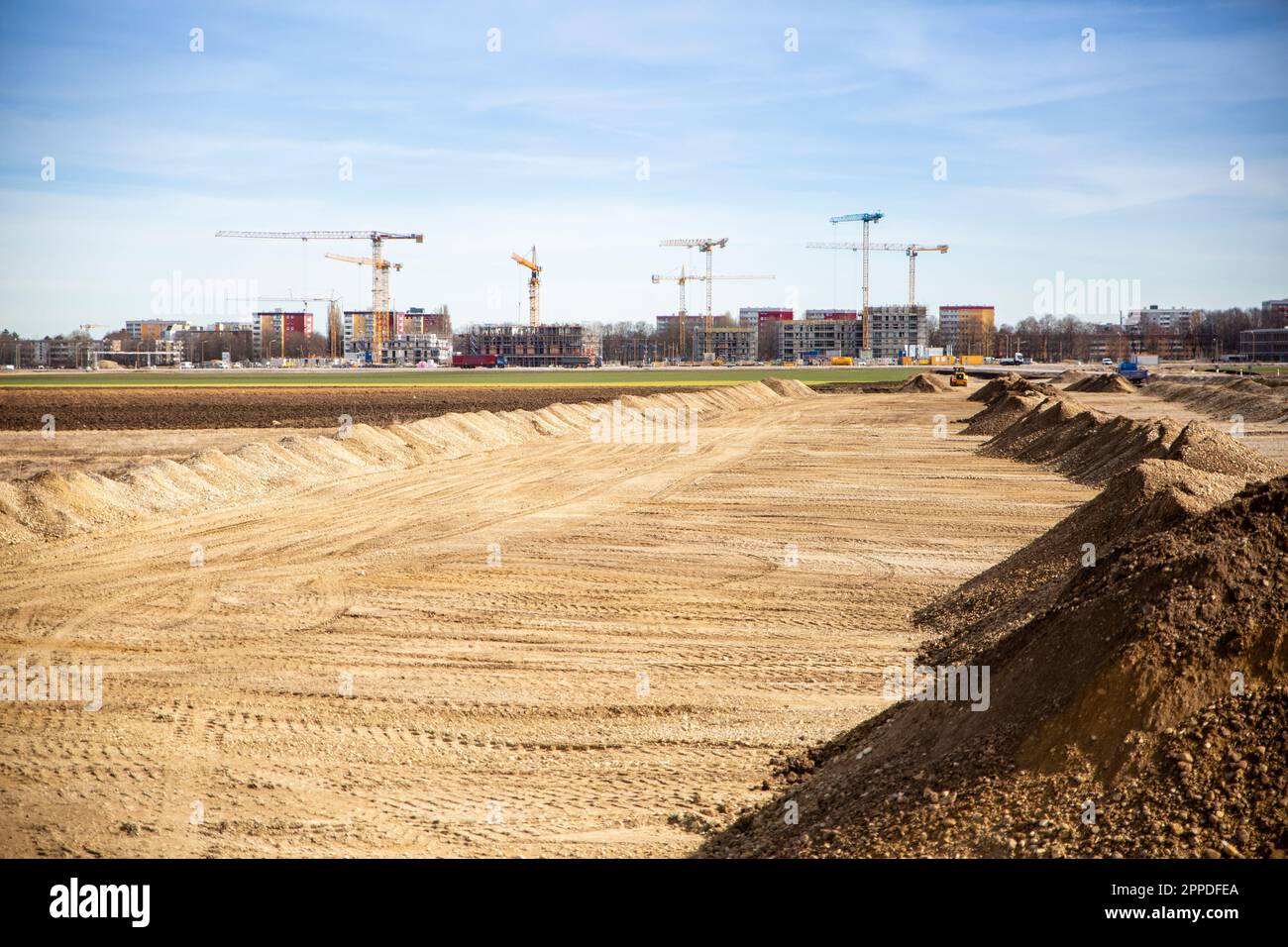 Germania, Baviera, Monaco di Baviera, Sandy zona preparata per cantiere con gru industriali in background Foto Stock