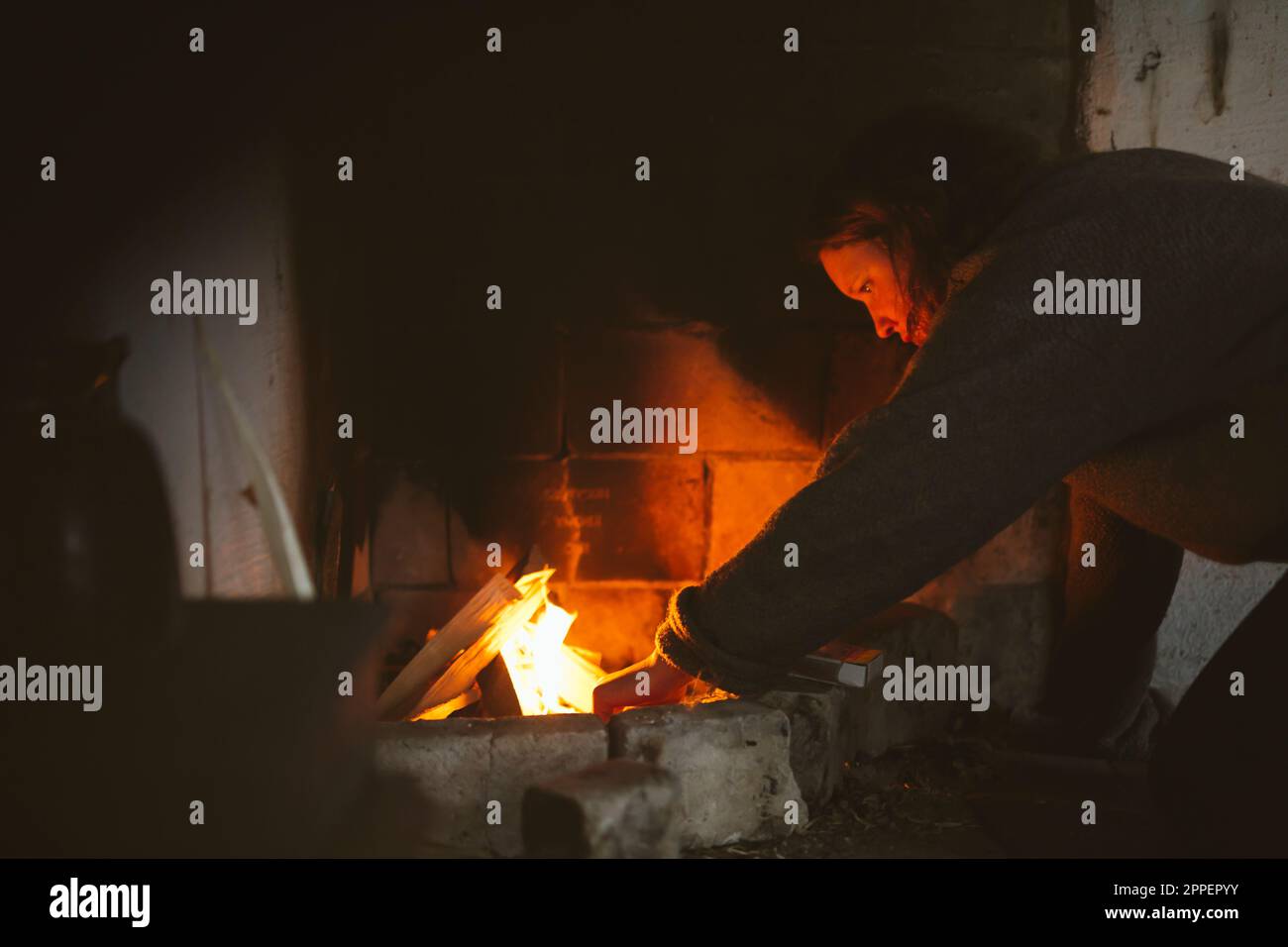 Donna che prepara legna da ardere in camino Foto Stock