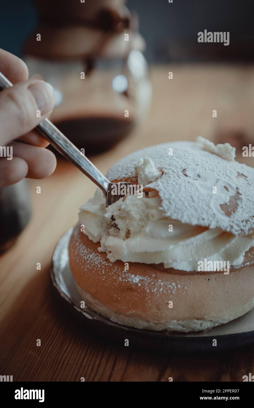 Persona che mangia tradizionale semla bun Foto Stock