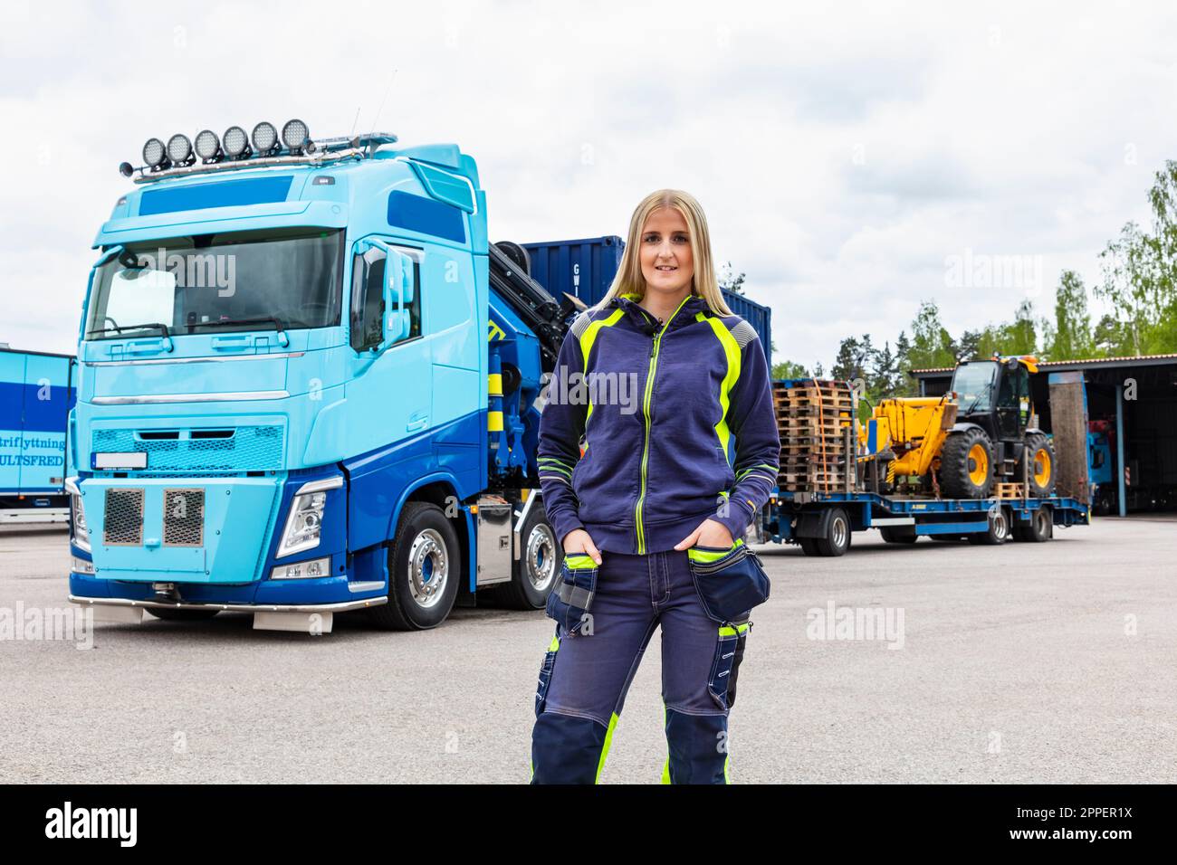 Donna bionda conducente di camion in piedi accanto al camion Foto Stock