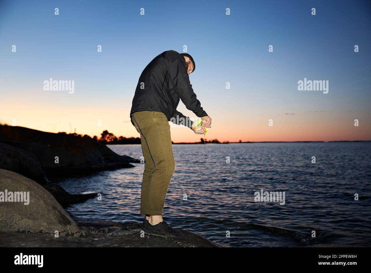 Uomo in piedi in mare al tramonto Foto Stock