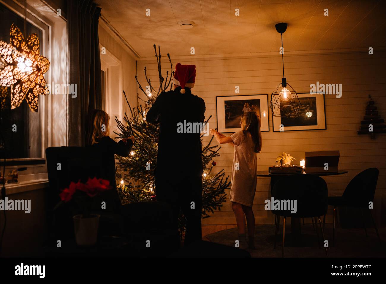 Padre e figlie che decorano l'albero di Natale Foto Stock
