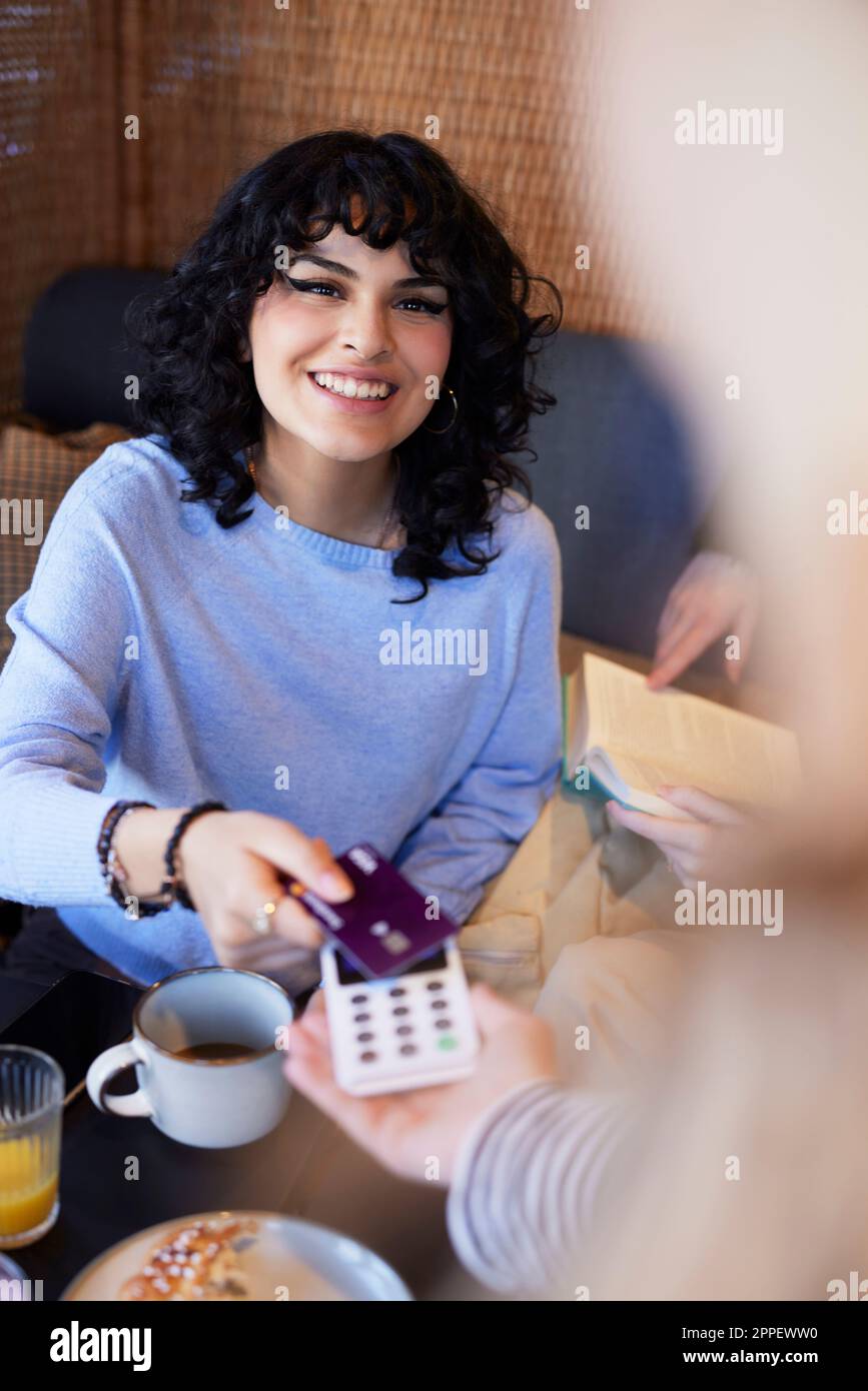 Giovane donna che paga con la carta nel caffè Foto Stock