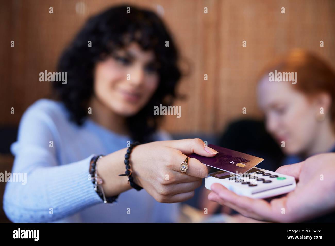 Giovane donna che paga con la carta nel caffè Foto Stock