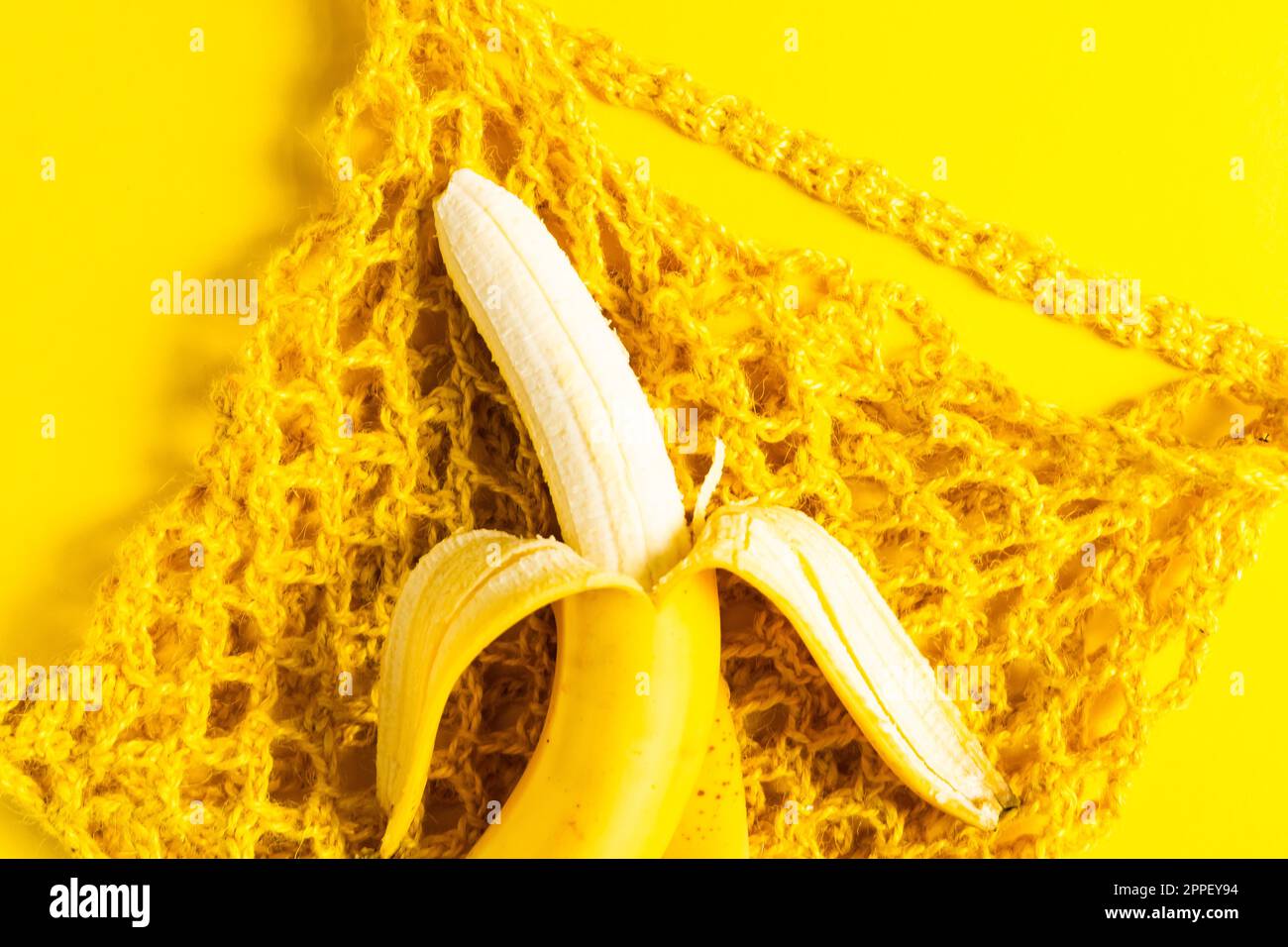 Una borsa a stringhe con banane isolate su sfondo giallo. Foto Stock