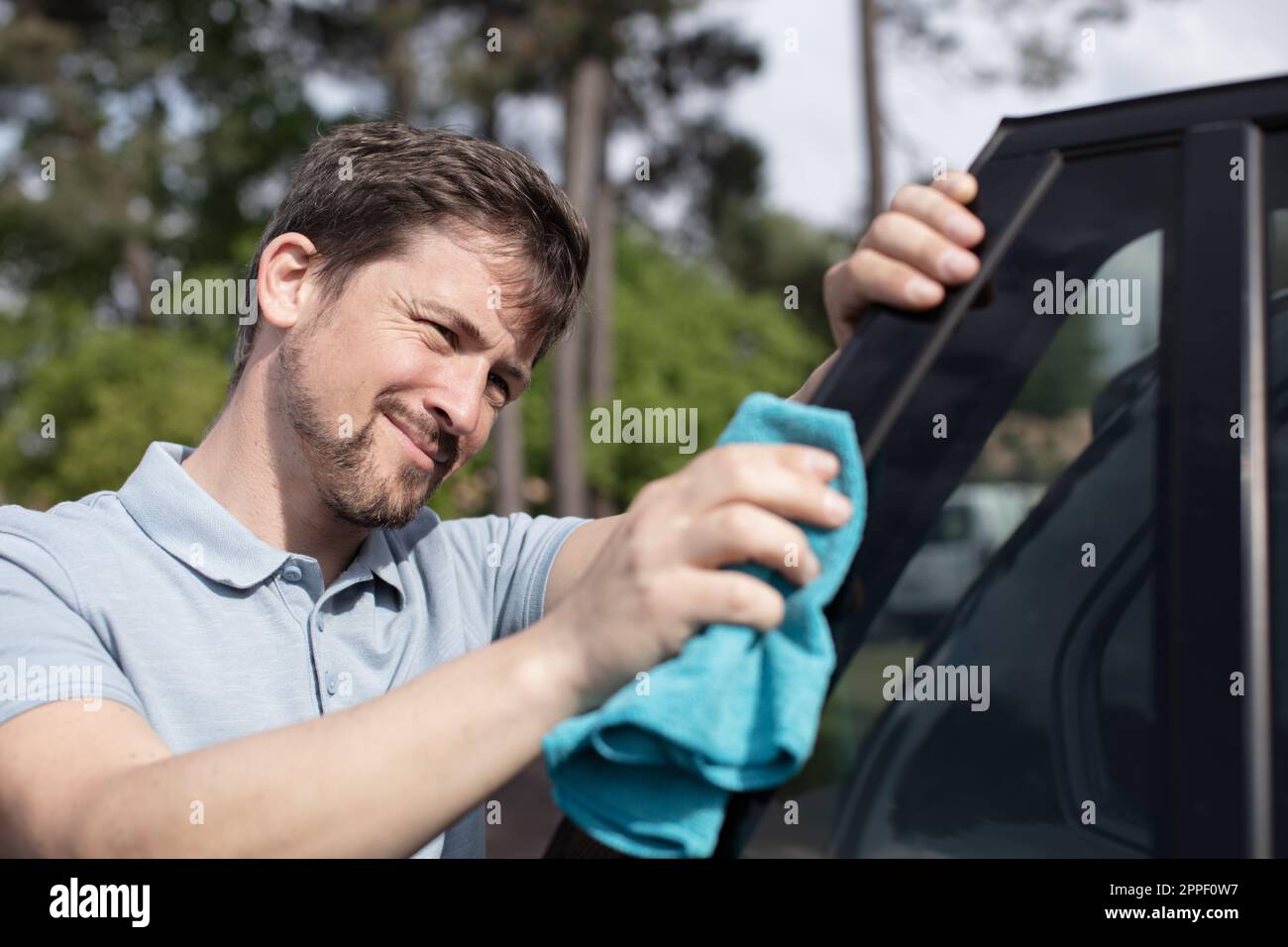 uomo lucidando la sua auto con panno microfibra di pulizia Foto Stock