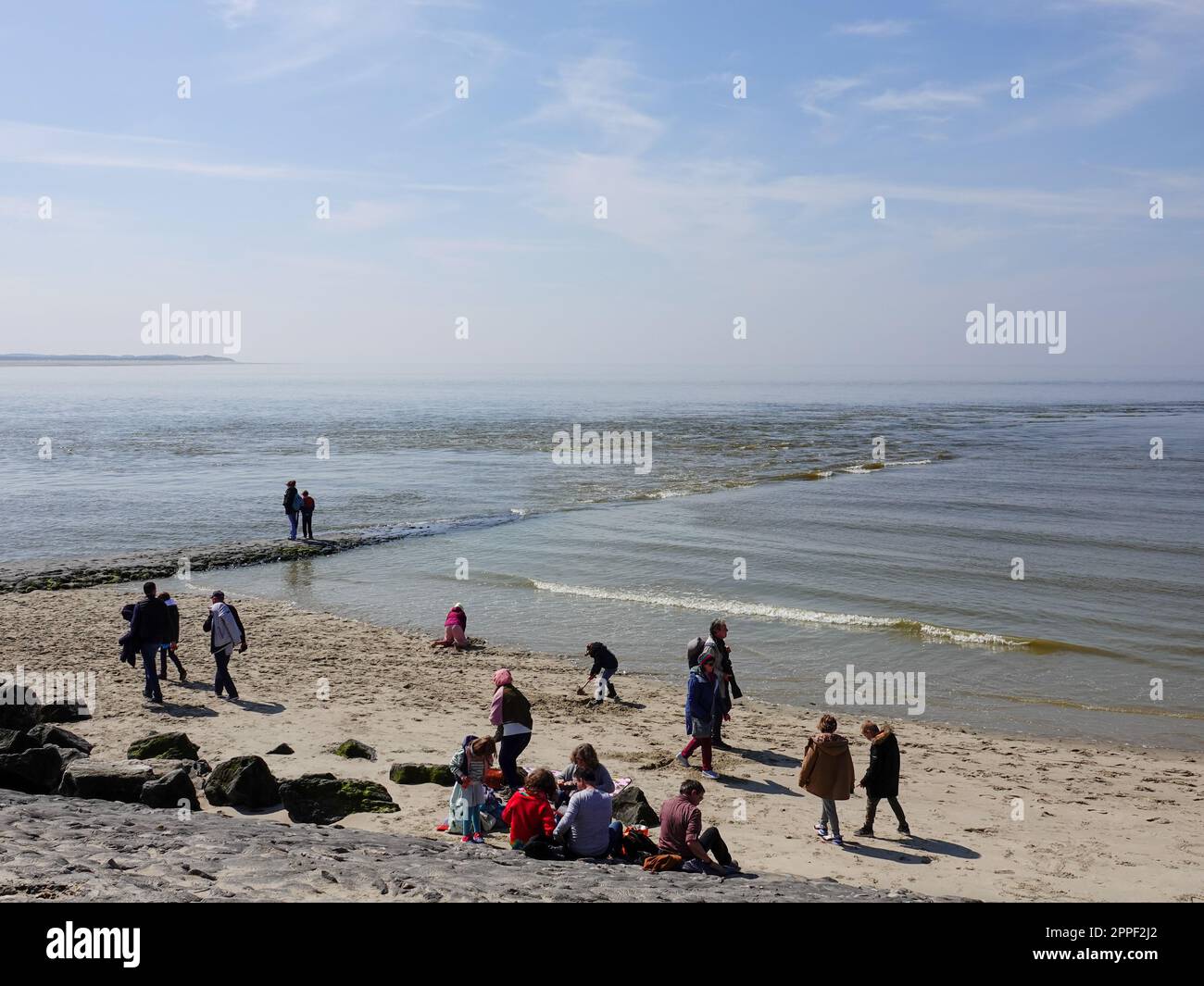 Persone sulla spiaggia, accanto a un molo, come la marea arriva a Berck-sur-Mer, Francia, sulla costa settentrionale. Foto Stock