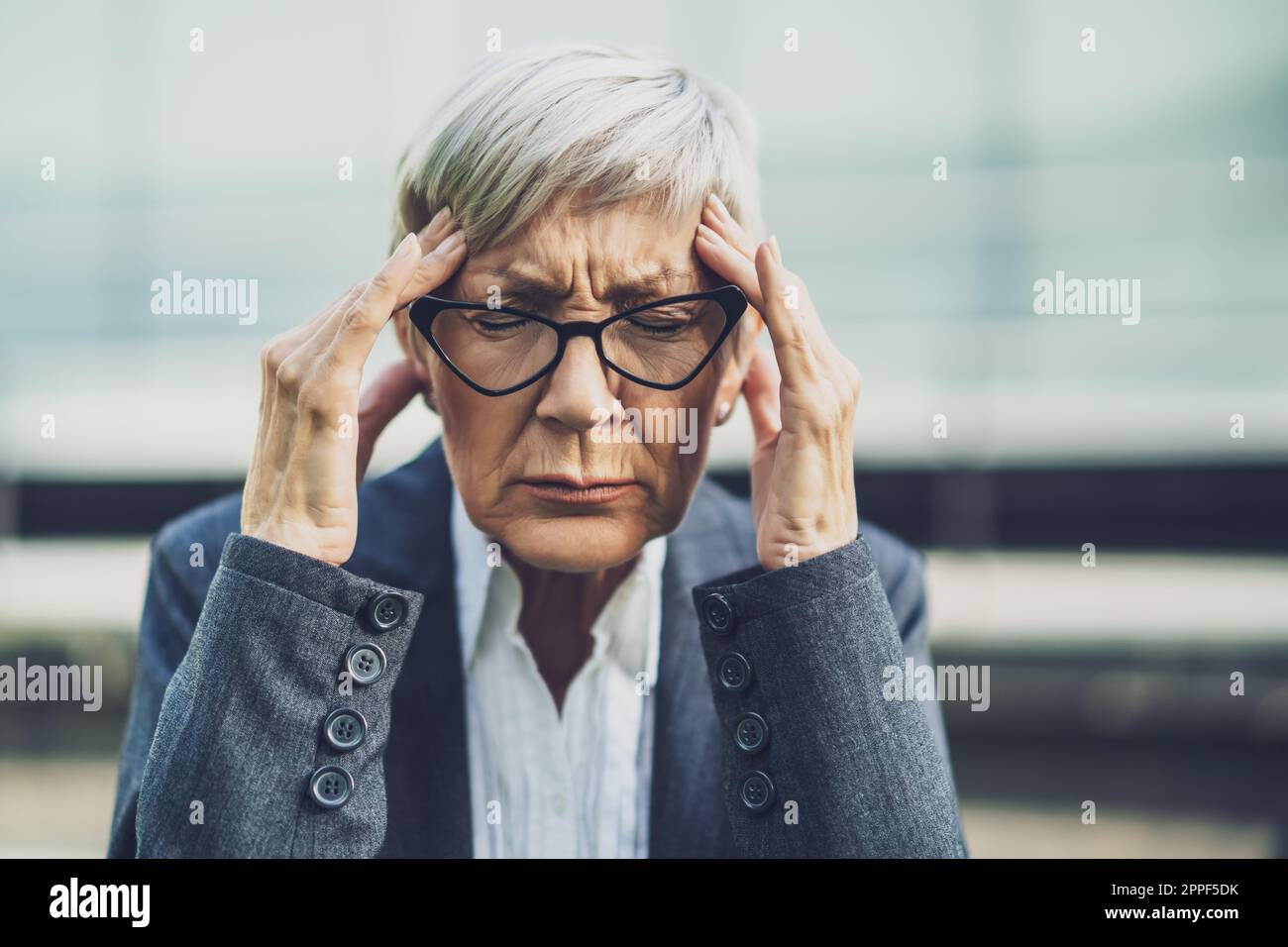 Primo piano ritratto di una donna d'affari matura che è sovraccarica e ha mal di testa. Foto Stock