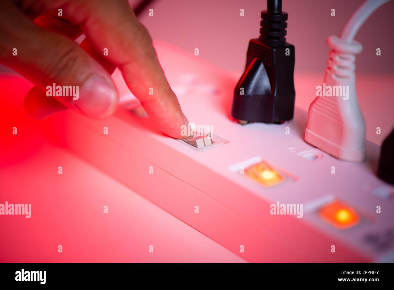 Primo piano una mano di mans spegnere l'interruttore sulla presa multipla. Foto Stock