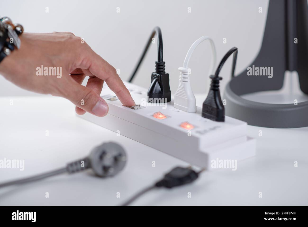 Primo piano una mano di mans spegnere l'interruttore sulla presa multipla. Foto Stock