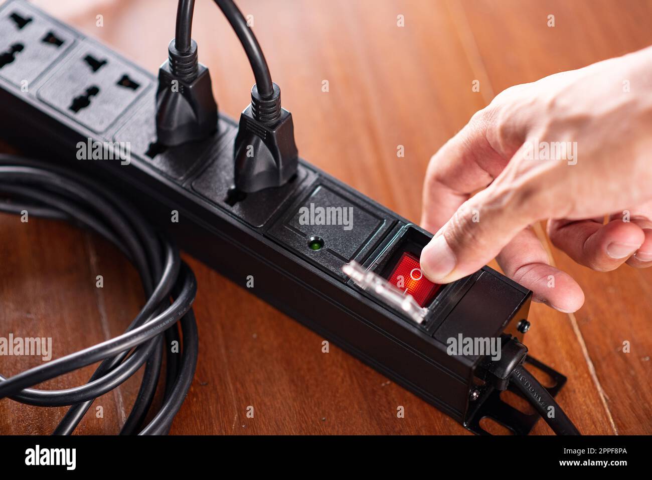 Primo piano una mano di mans accendere l'interruttore sulla presa multipla. Foto Stock
