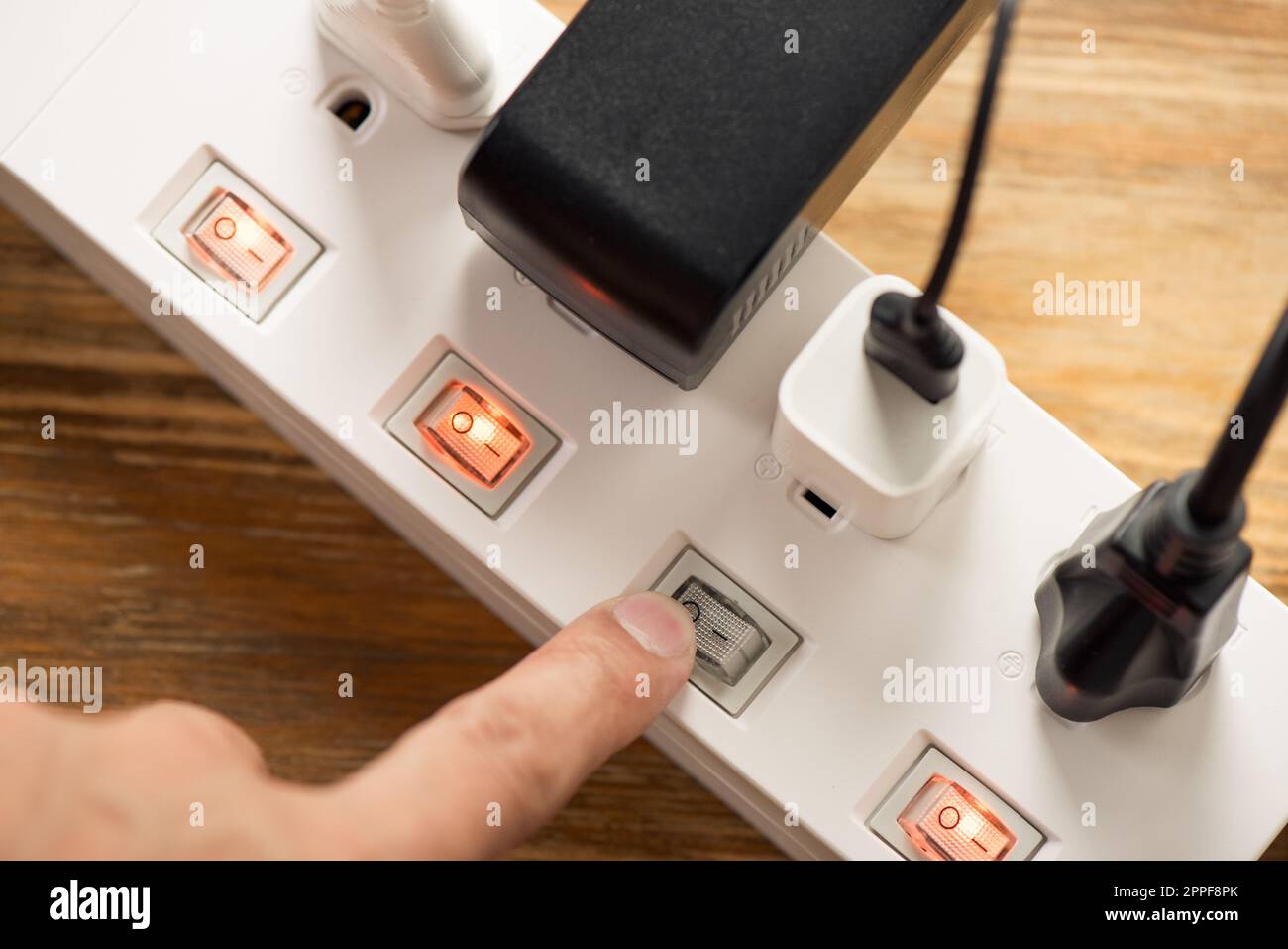 Primo piano una mano di mans spegnere l'interruttore sulla presa multipla. Foto Stock