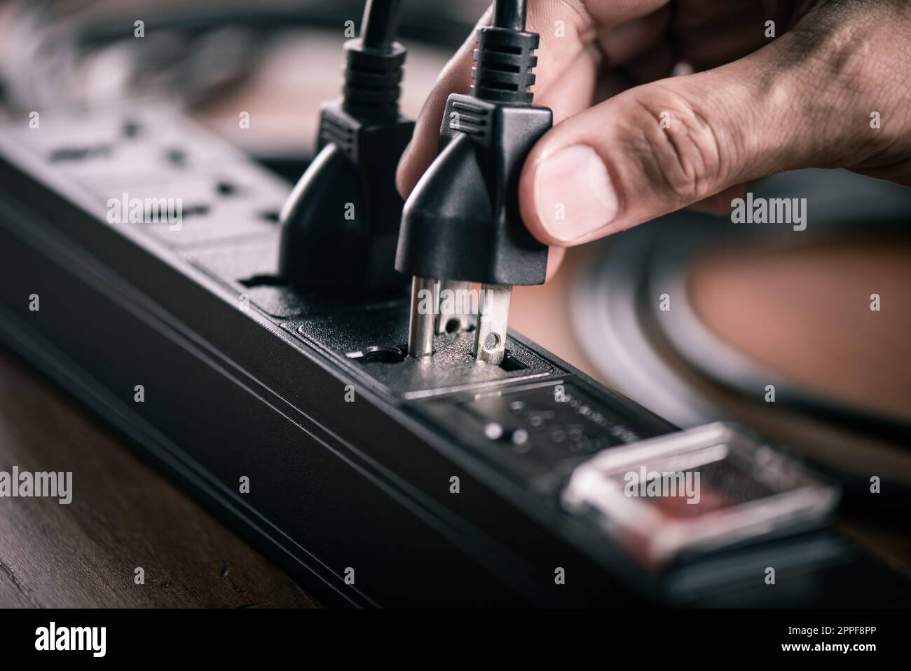 Primo piano di una mano di mans che inserisce una spina nella presa multipla elettrica. Foto Stock