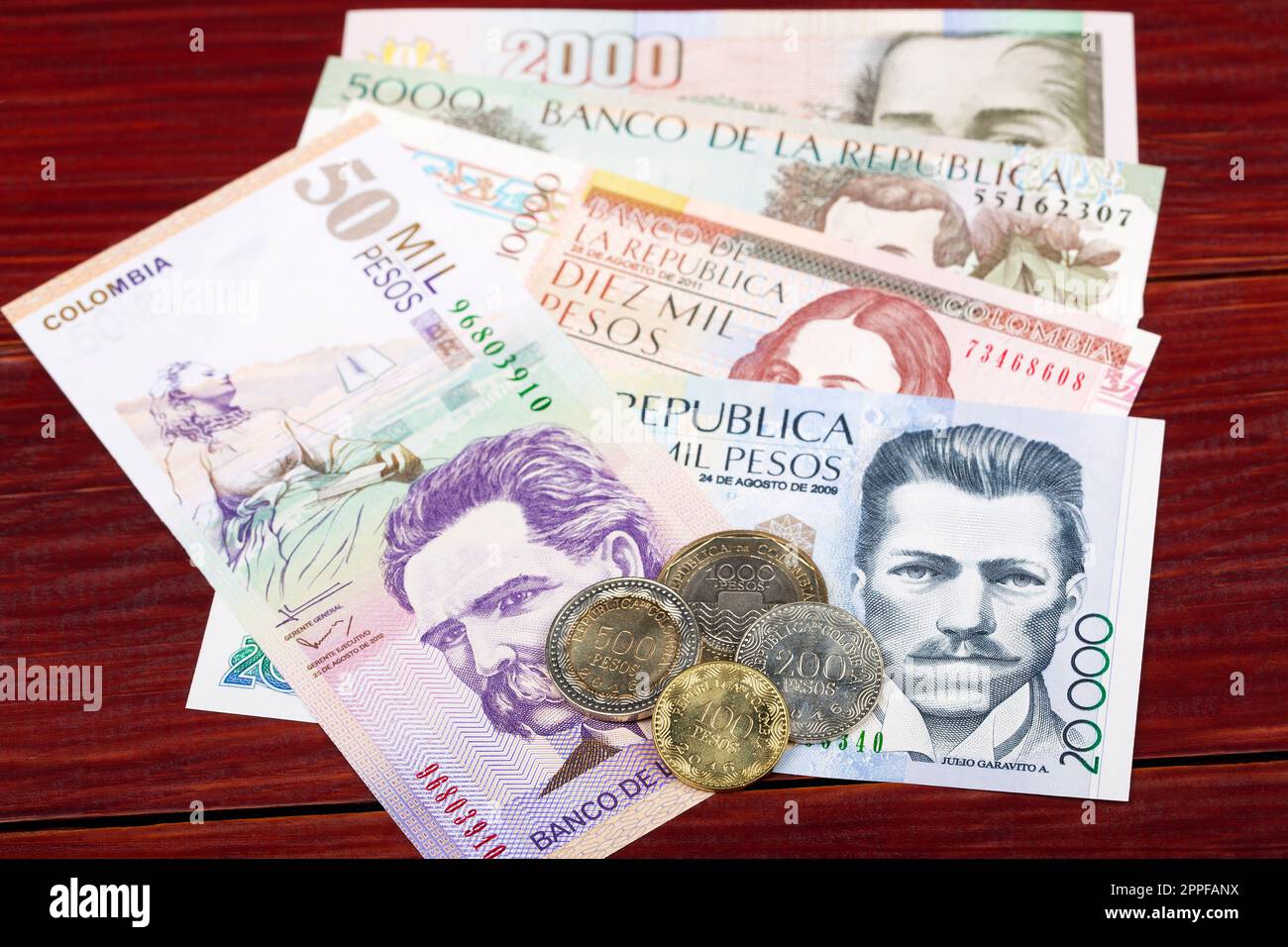 Monete e banconote di pesos colombiani su sfondo ligneo Foto Stock