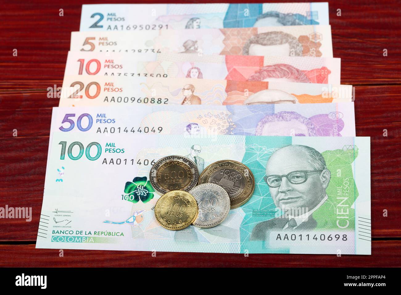 Monete e banconote di pesos colombiani su sfondo ligneo Foto Stock