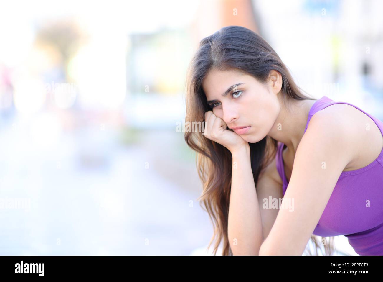 Annoiato donna in attesa di sedersi in strada Foto Stock