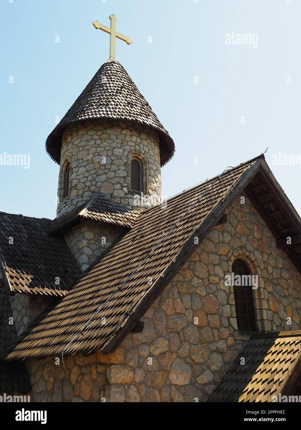 Chiesa ortodossa in pietra nel parco etno. Turismo religioso. Un edificio fatto di pietre con una croce sulla cupola. Cielo blu Foto Stock