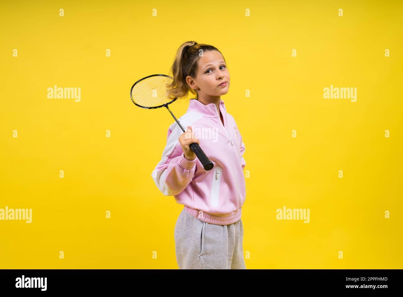 Foto di studio di lunghezza intera di una ragazza di dieci anni con racchetta di badminton e isolata sul giallo. Foto Stock