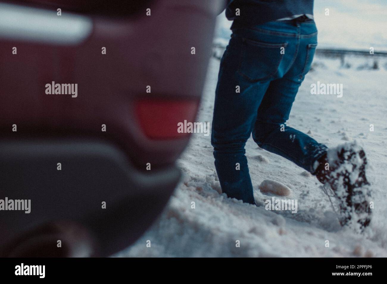 Un maschio di mezza età con una macchina fotografica cammina attraverso la neve. Foto Stock