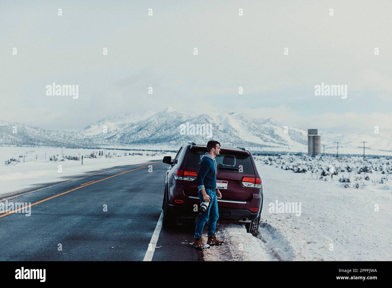 Un maschio di mezza età scatta una fotografia sulla neve. Foto Stock