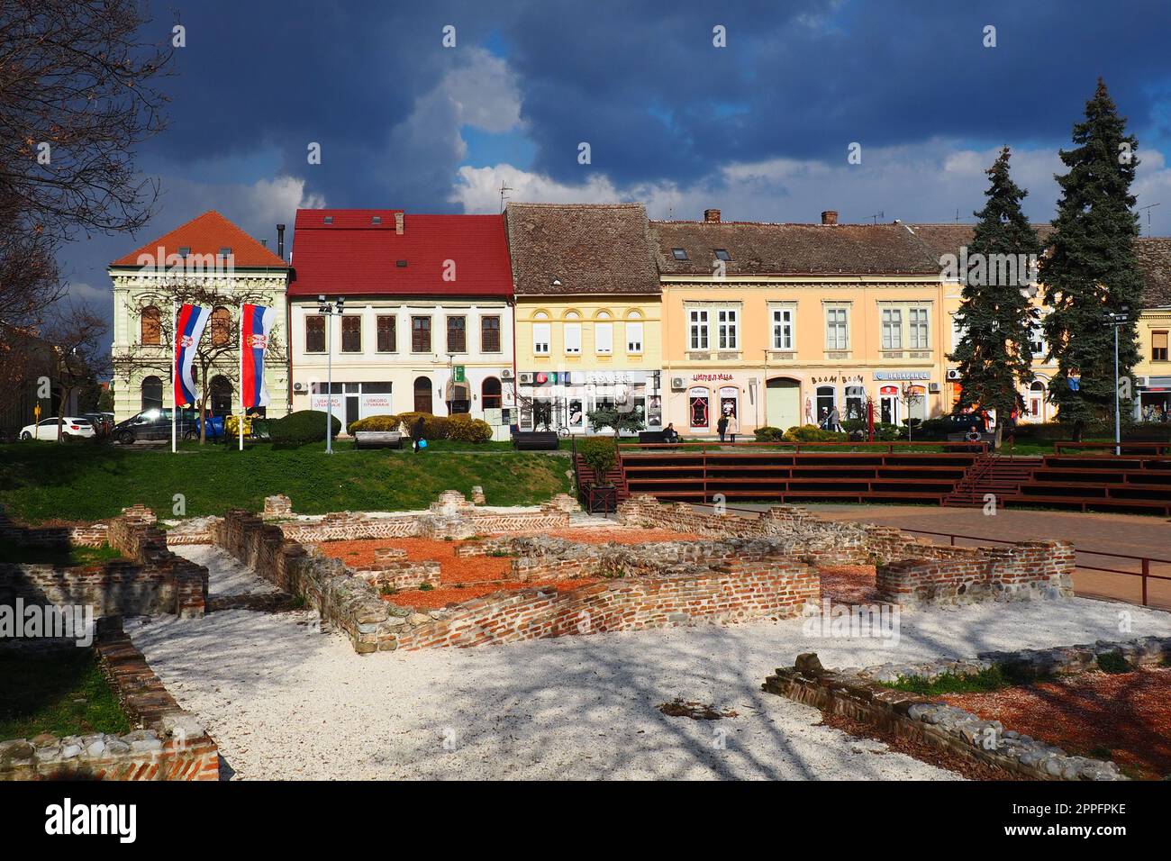 Sremska Mitrovica, Serbia, 16 marzo 2023 piazza storica Zitni trg. Antichi edifici multicolori e scavi di epoca romana. Patrimonio culturale. Cielo drammatico. Scavi di camere romane. Foto Stock