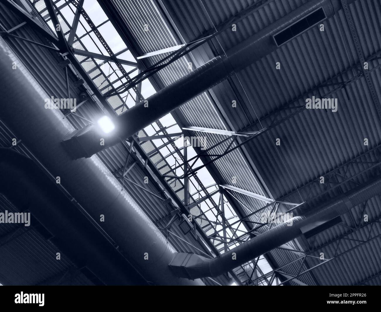 Il tetto di un hangar, di una sala di produzione o di un palazzetto dello sport. Strutture metalliche, travi, elementi di supporto. Sistemi di ventilazione in grandi sale e stanze. Lucernari. Interni industriali. Foto Stock