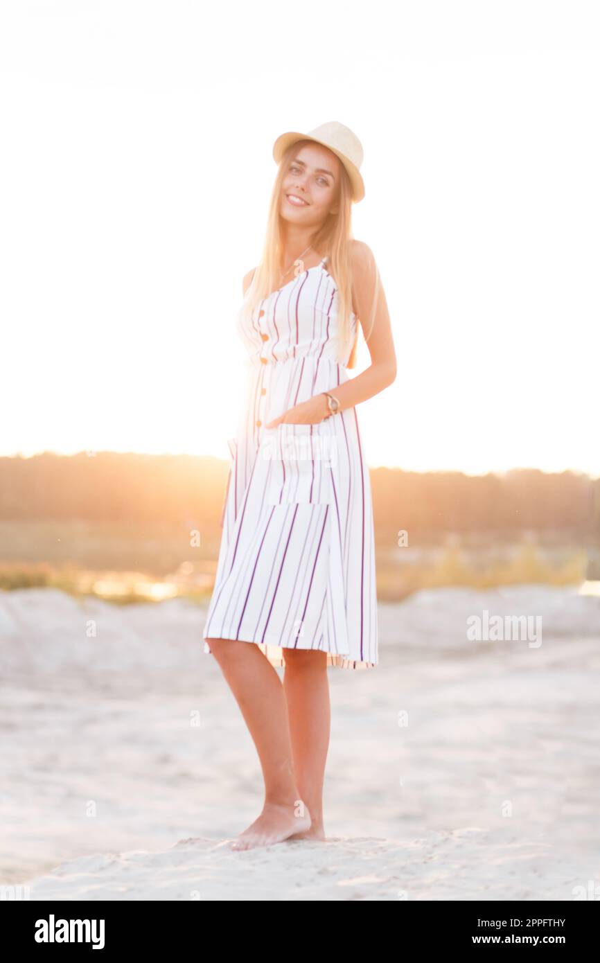 giovane bionda in cappello e abito estivo in spiaggia Foto Stock