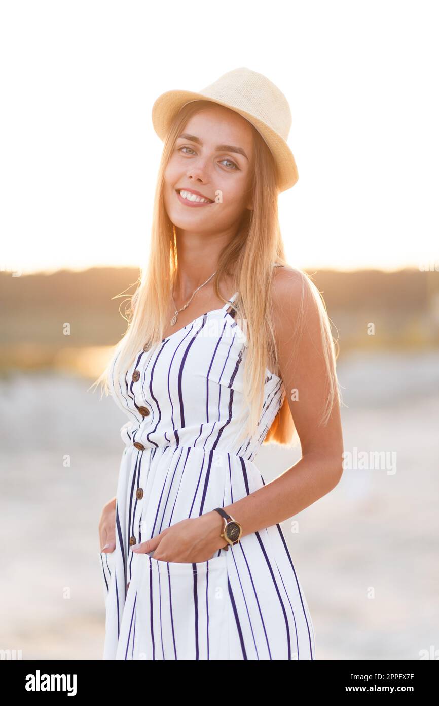 giovane bionda in cappello e abito estivo in spiaggia Foto Stock