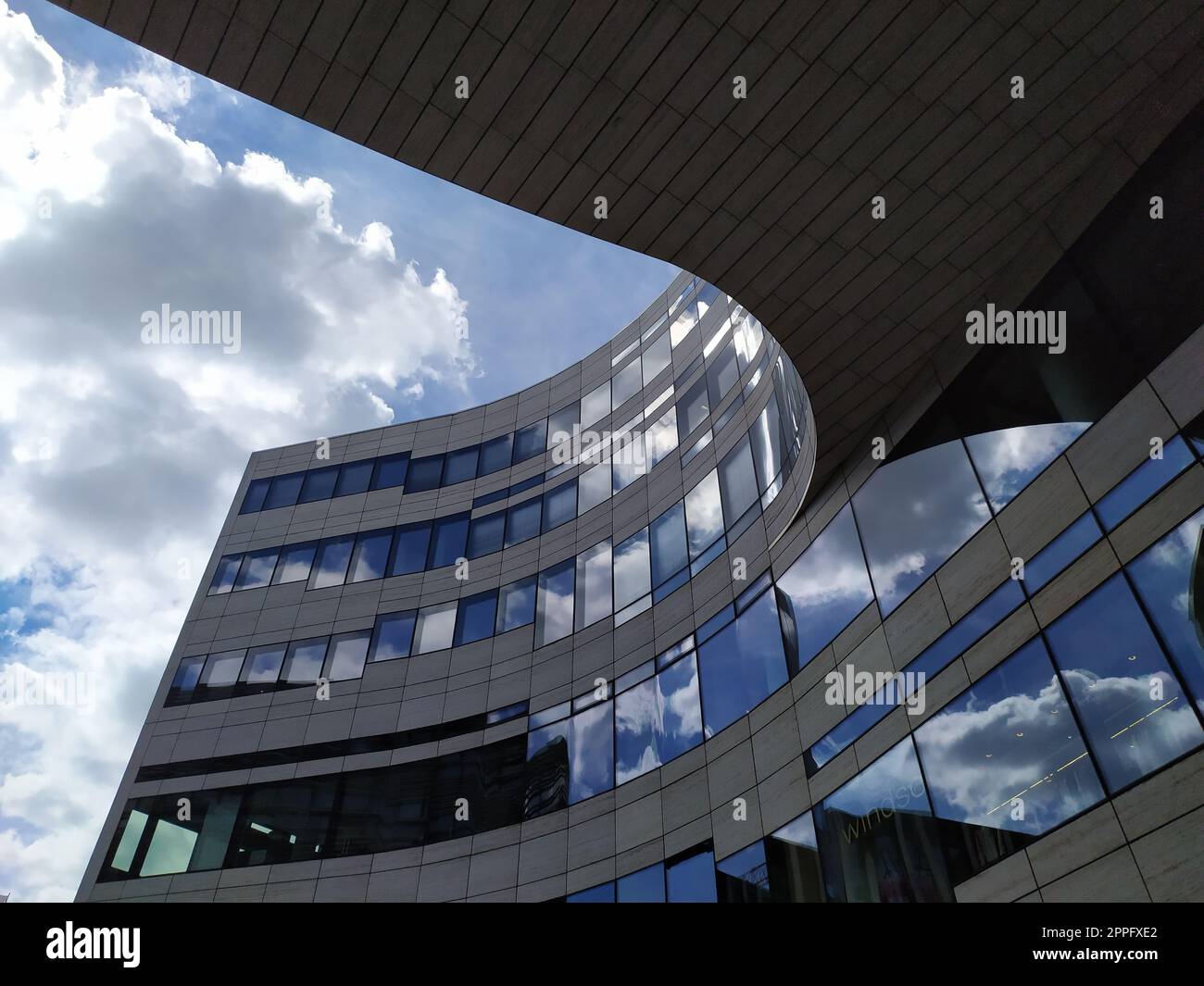 Dusseldorf, Germania - 16 luglio 2022: L'architettura moderna del DÃ¼sseldorfer KÃ¶bogen in estate mostra una facciata in vetro attraente e stravagante di un centro commerciale organico e curvo con nuvole blu Foto Stock