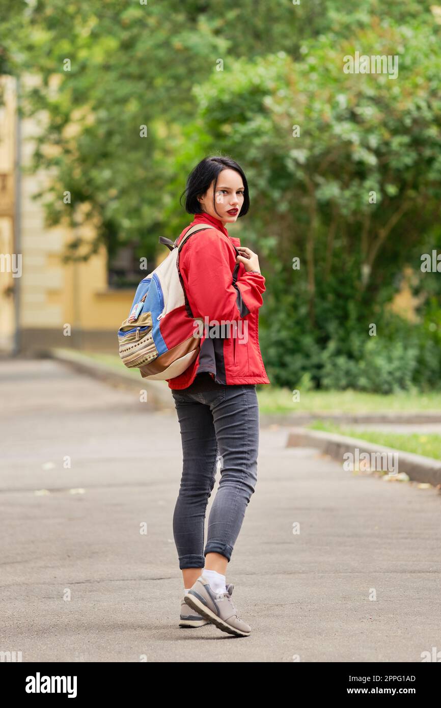 Tourist ragazza con zaino tela guardando indietro sulla strada Foto Stock