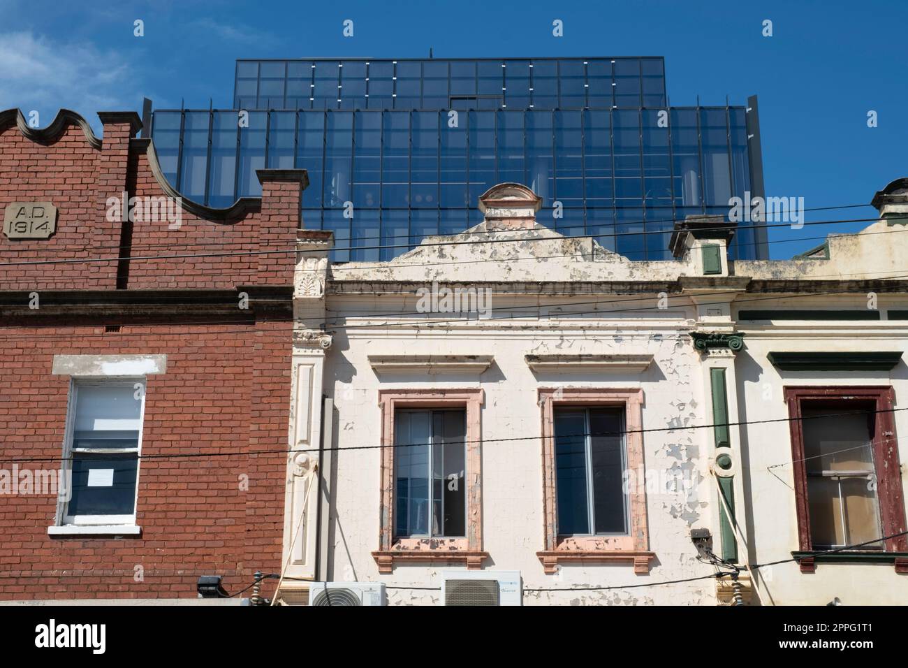 Le storiche facciate coloniali, vecchie e decorate al tempo, sono in primo piano e un moderno edificio in vetro sullo sfondo di Melbourne. Vecchio e nuovo Foto Stock