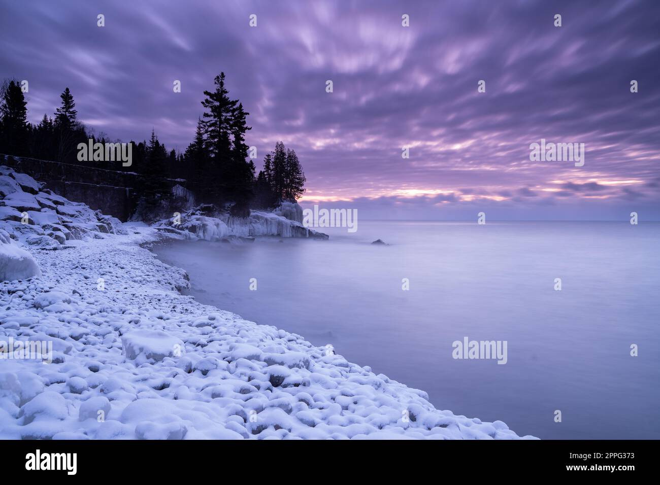 Alba con i toni Viola sulla riva del lago d'inverno Foto Stock