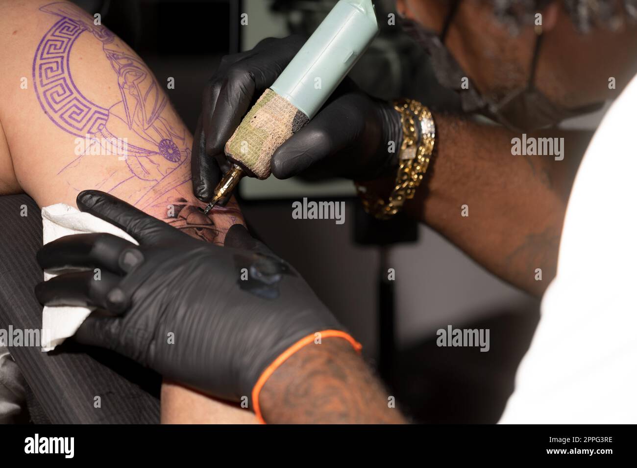 Vista ravvicinata del processo di tatuaggio. Master crea linee di contornatura con la sua macchina per tatuaggio professionale. Foto Stock