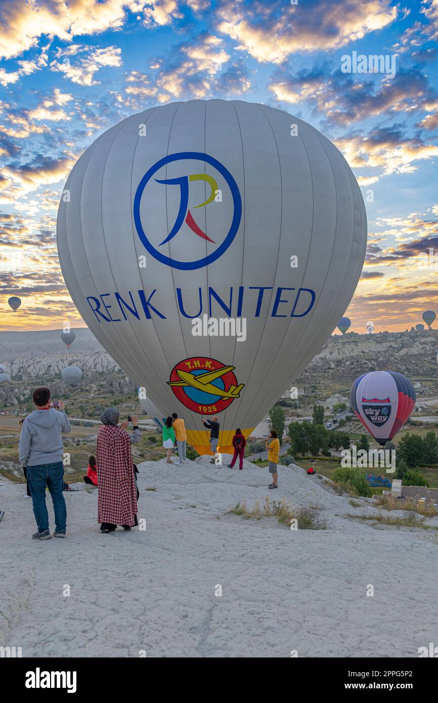 la mongolfiera vola vicino ai turisti sulle colline di goreme. Foto Stock