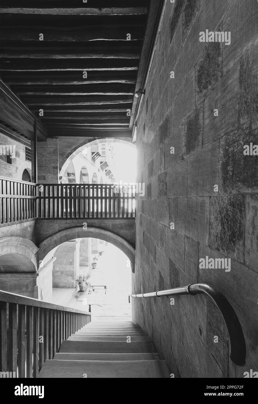 Foto in bianco e nero della scala che scende con balaustra di legno in un vecchio edificio storico abbandonato Foto Stock