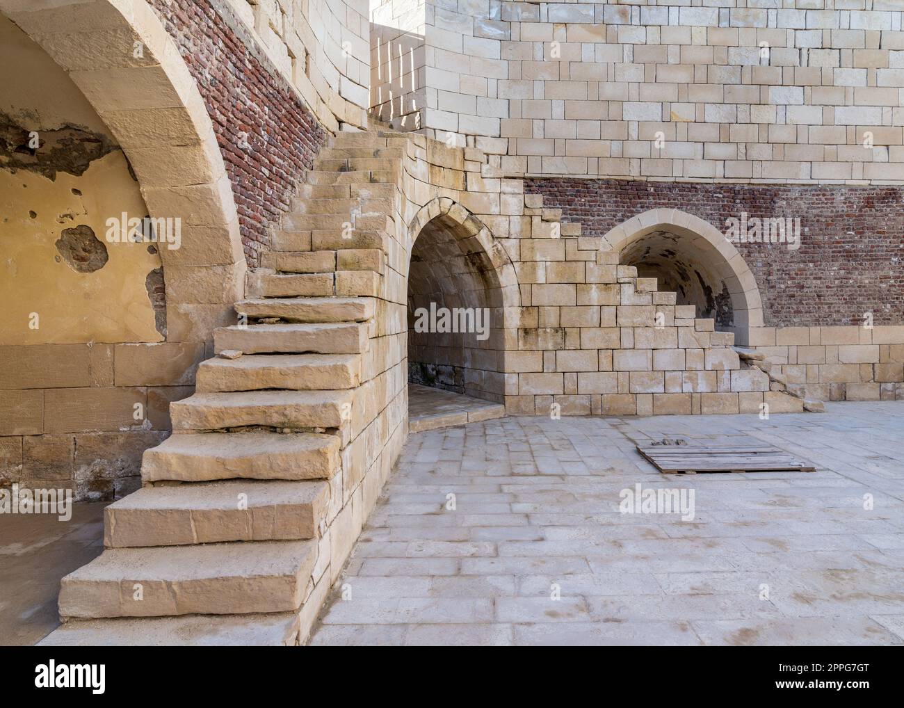 Antico edificio in mattoni con due scalinate in pietra e due alcove ad arco in rovina sulla strada Foto Stock