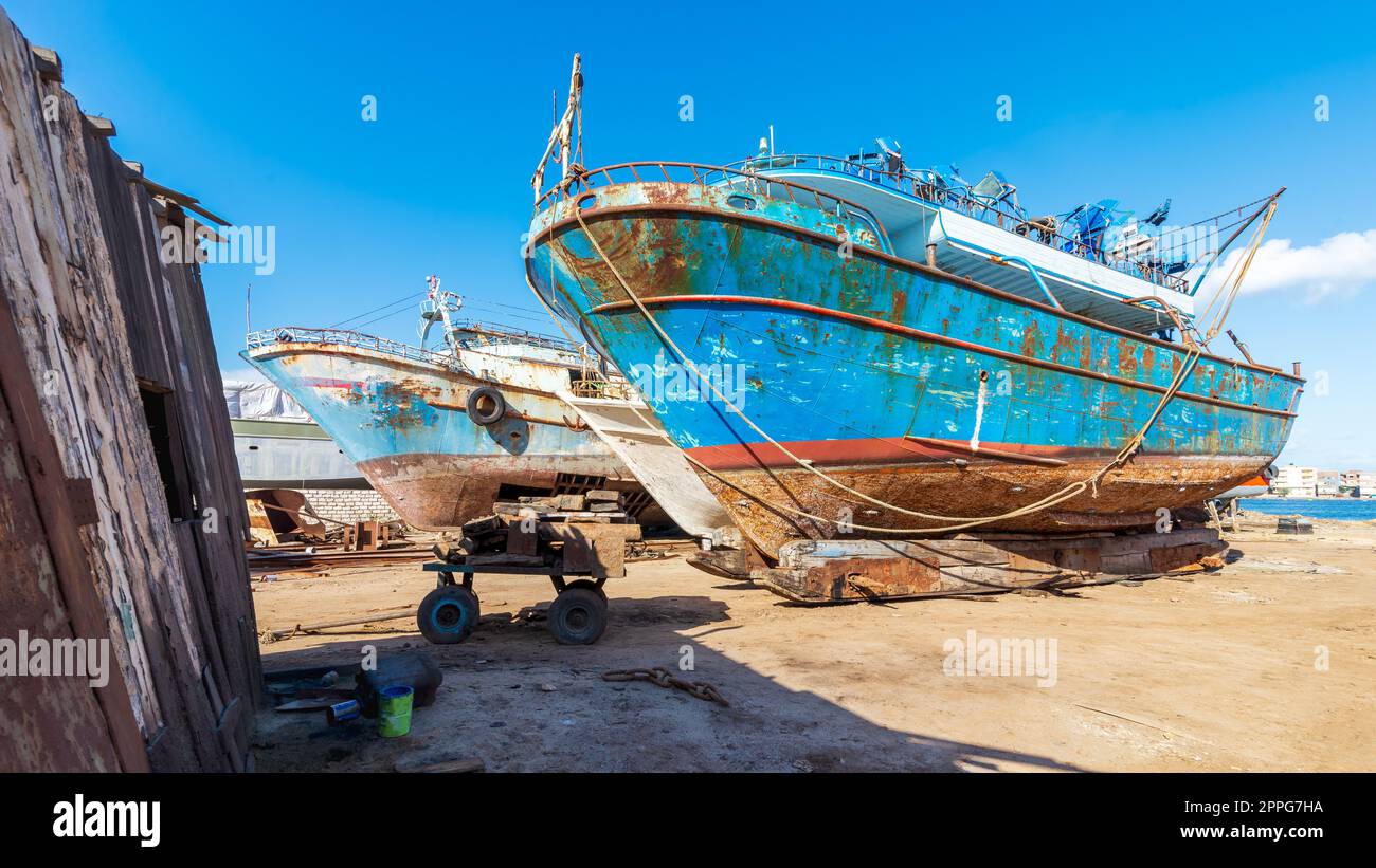 Vecchia nave arrugginita in riparazione su un bacino di carenaggio grintoso nel cantiere navale di un vecchio impianto di costruzione navale Foto Stock