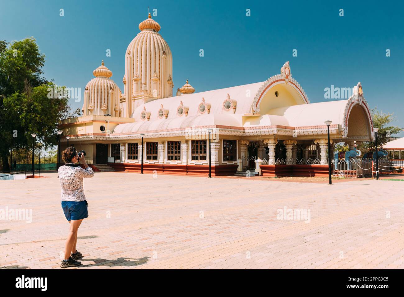 Mapusa, Goa, India. Giovane donna turista fotografa fotografando vicino a Shree Ganesh Mandir, al tempio di Ganeshpuri. Famoso punto di riferimento e popolare destinazione Foto Stock