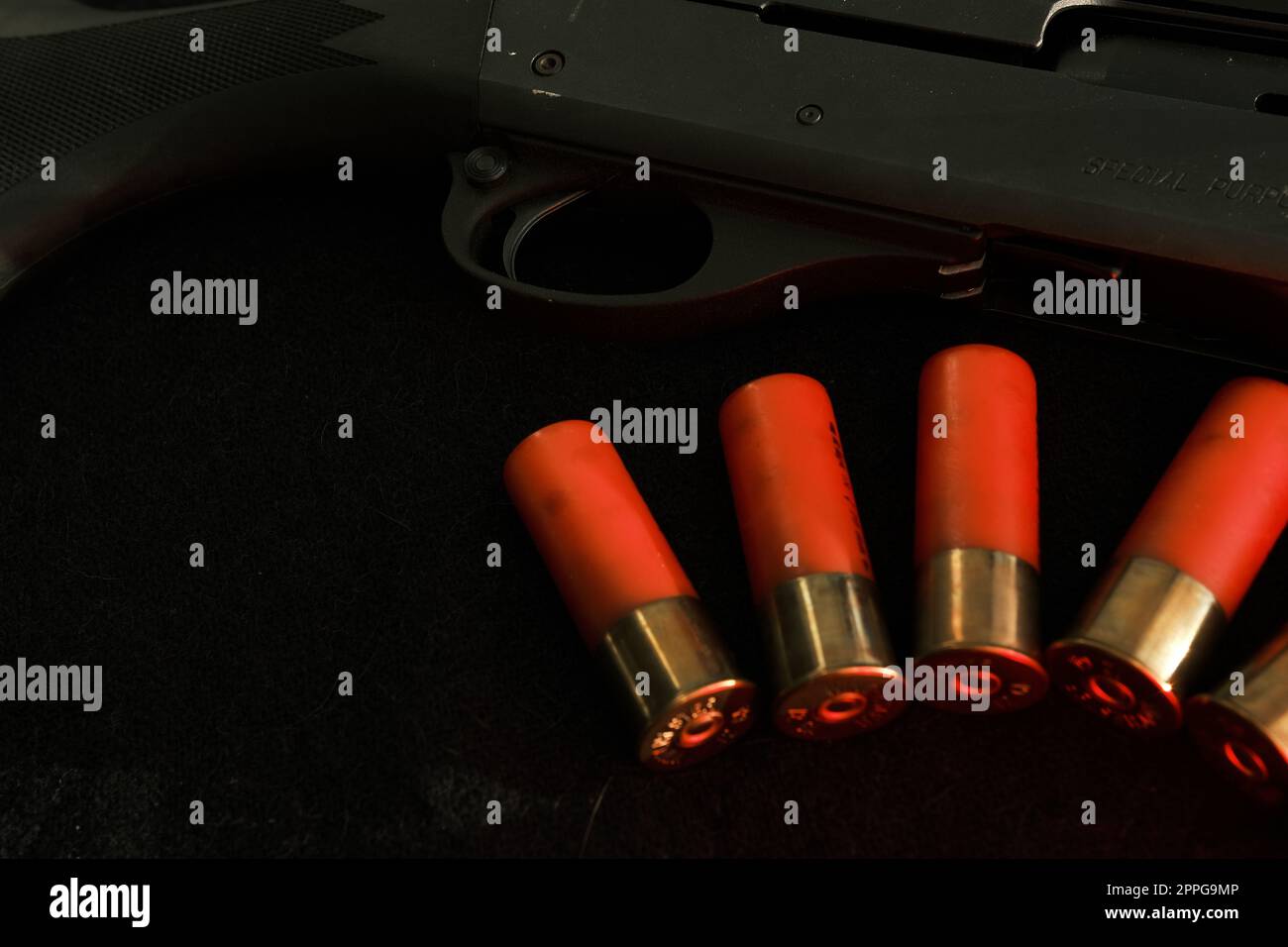 Grilletto di un fucile su sfondo nero con fulmine rosso con proiettili Shotgun su una superficie nera. Munizioni per armi a foro liscio da 12 gauge. Caccia alle munizioni. Sfondo scuro. Foto Stock