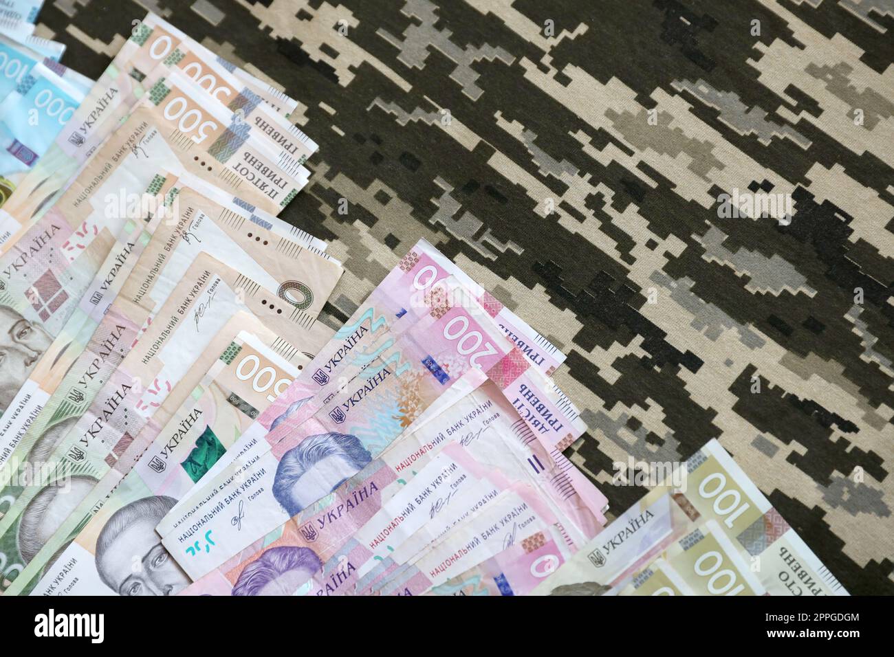 L'hryvnya ucraino fattura sul tessuto con la tessitura del camouflage pixeled militare ucraino. Panno con motivo camo in pixel grigio, marrone e verde Foto Stock
