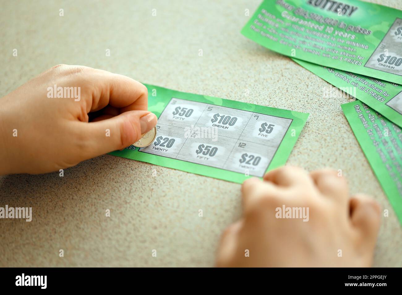 Vista ravvicinata della moneta d'argento in mano a una falsa carta della lotteria che gratta il giocatore d'azzardo. Concetto di gioco della lotteria, lotteria per graffiare le carte Foto Stock