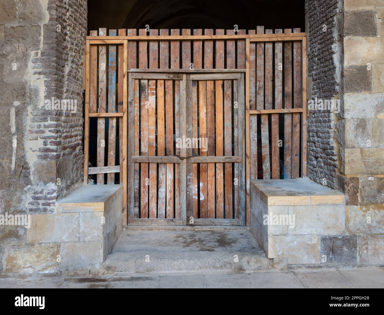 Porta in legno malandato di un edificio in pietra Foto Stock