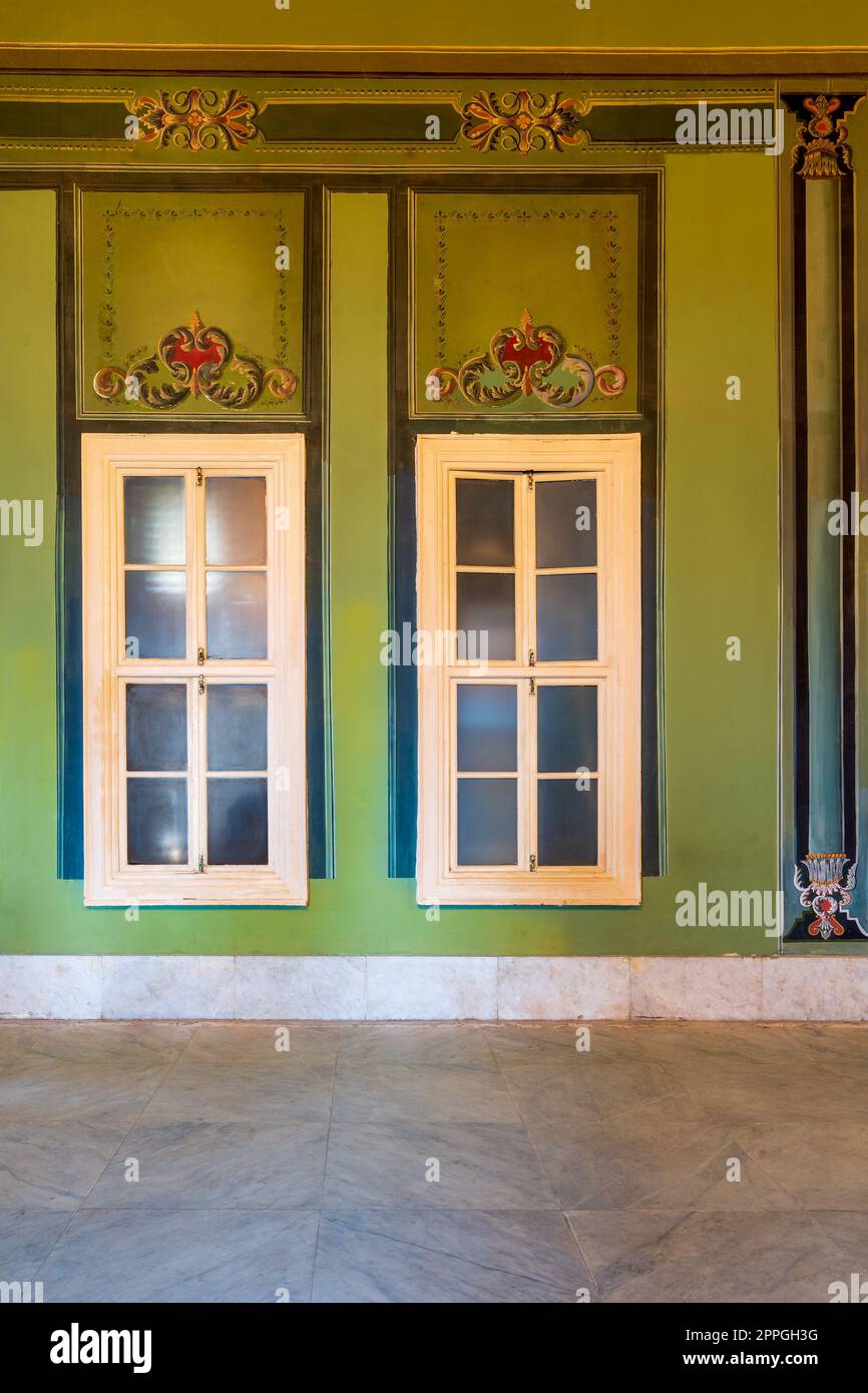 Finestre chiuse e bellissime ed eleganti cornici intagliate su pareti verdi con bordo decorato e pavimento in marmo Foto Stock