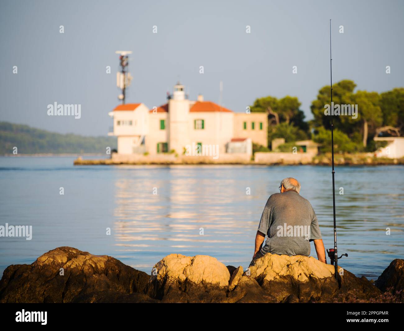 pensionato è seduto e pesca sul canale di sveti ante in croazia sibenik Foto Stock