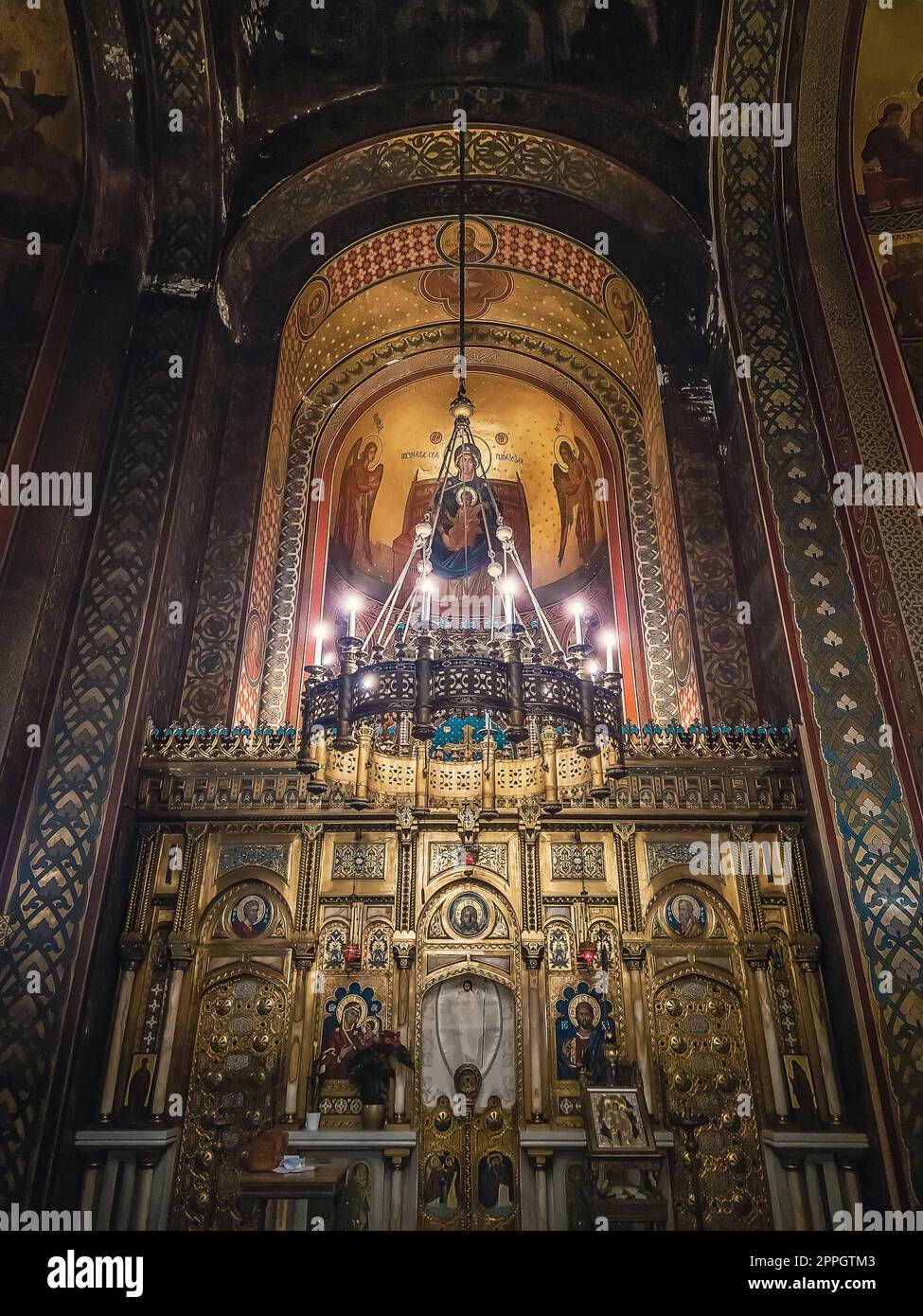 Dettagli interni del monastero di Curtea de Arges. L'altare e le pareti ornate con icone dipinte e un lampadario dorato con luci che si sospendono al di fuori del soffitto Foto Stock