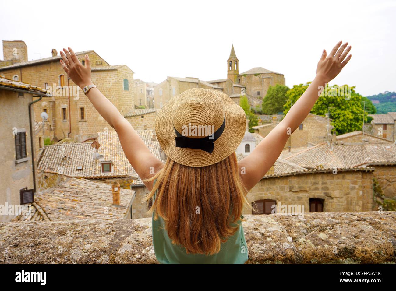 Felice giovane donna con le braccia in su nella città di Orvieto. Ragazza viaggiatore con le braccia tese sollevata sulla città. Turista in vacanza di viaggio nel centro Italia. Foto Stock