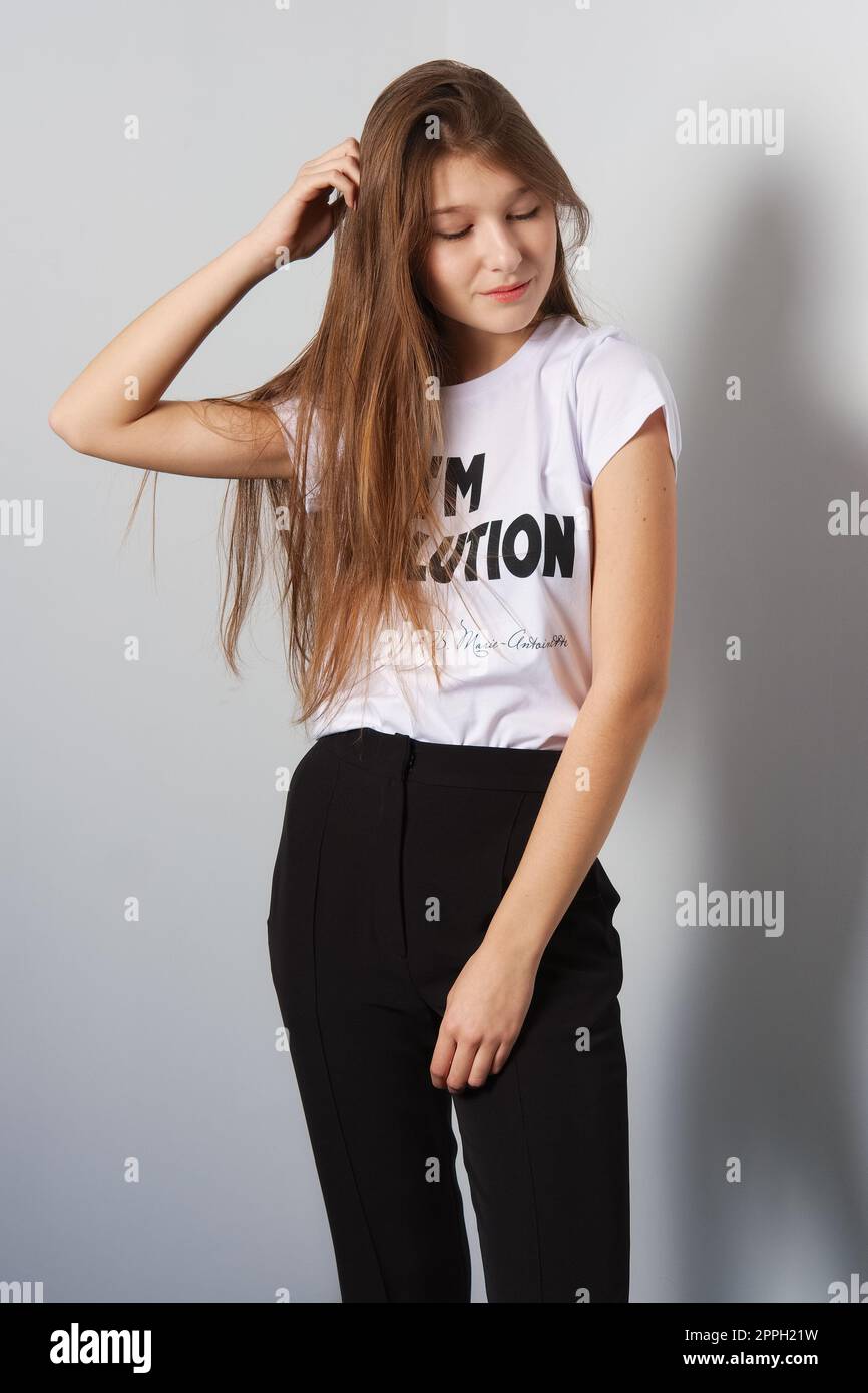 Attraente modello di moda in pantaloni e t-shirt con iscrizione che tocca i suoi capelli Foto Stock