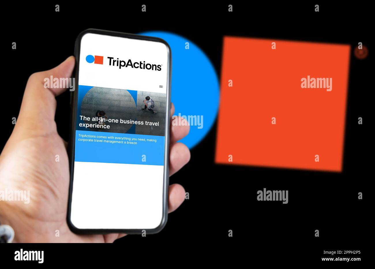 Mano tenendo un telefono con la homepage di Tripactions sullo schermo Foto Stock