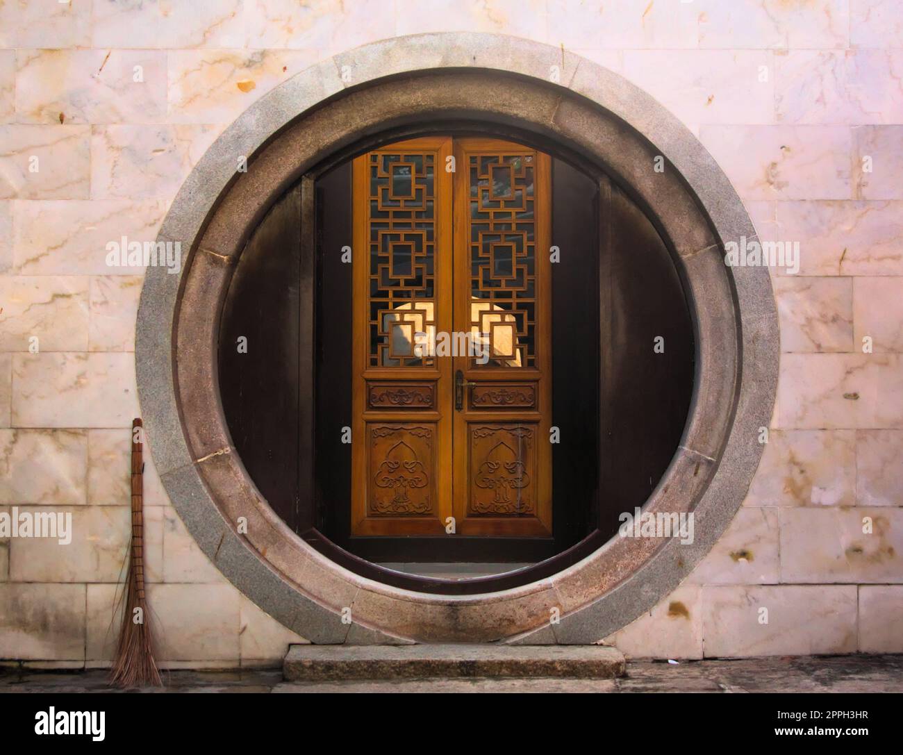 Arco di pietra circolare e porta di legno in un tempio buddista cinese a Saigon, Vietnam. Foto Stock