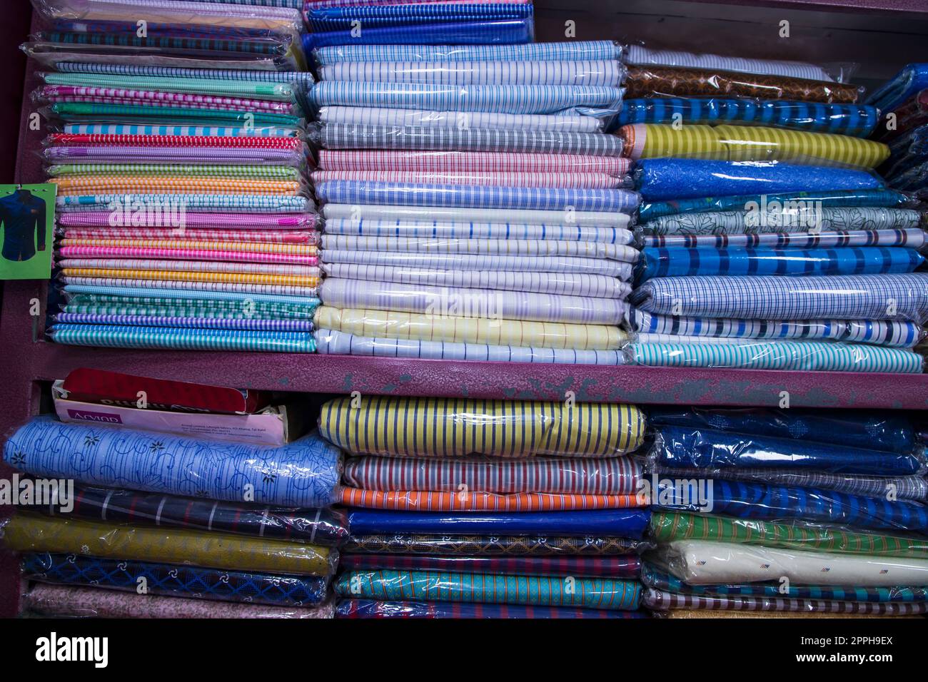 Tessuti a motivi tessili impilati su un negozio al dettaglio Shelf in vendita Foto Stock